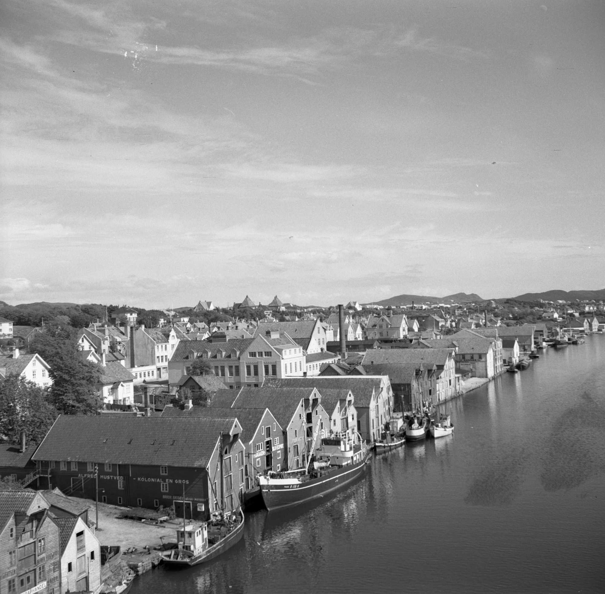 Langs Smedasundet ligger flere båter, bak disse sjøhus. Lenger til v. i bildet mange byhus. Midt i bildet er en stor murbygning - det gamle slaktehuset. Bildet er antagelig tatt fra Risøybroen.