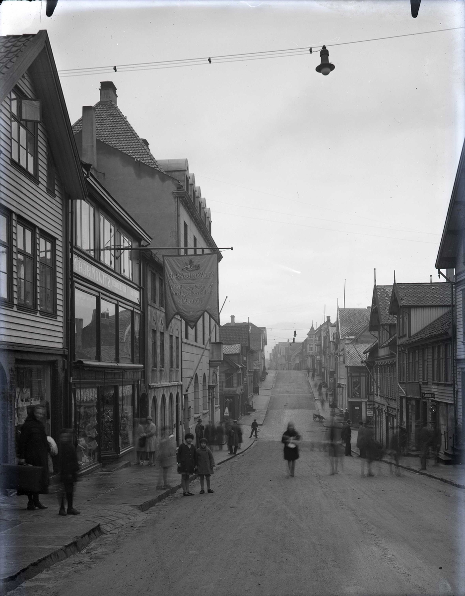 Strandgt. fotografert mot sør. M. Rabinowitz forretning til venstre.
I Torgbakken ses Slumsøstrenes julegryte: Juleinnsamling til byens fattige.