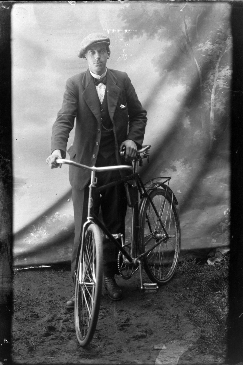Studioportrett i helfigur av en mann med sykkel.