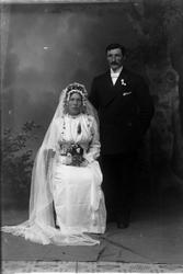 Studioportrett i helfigur av et brudepar.