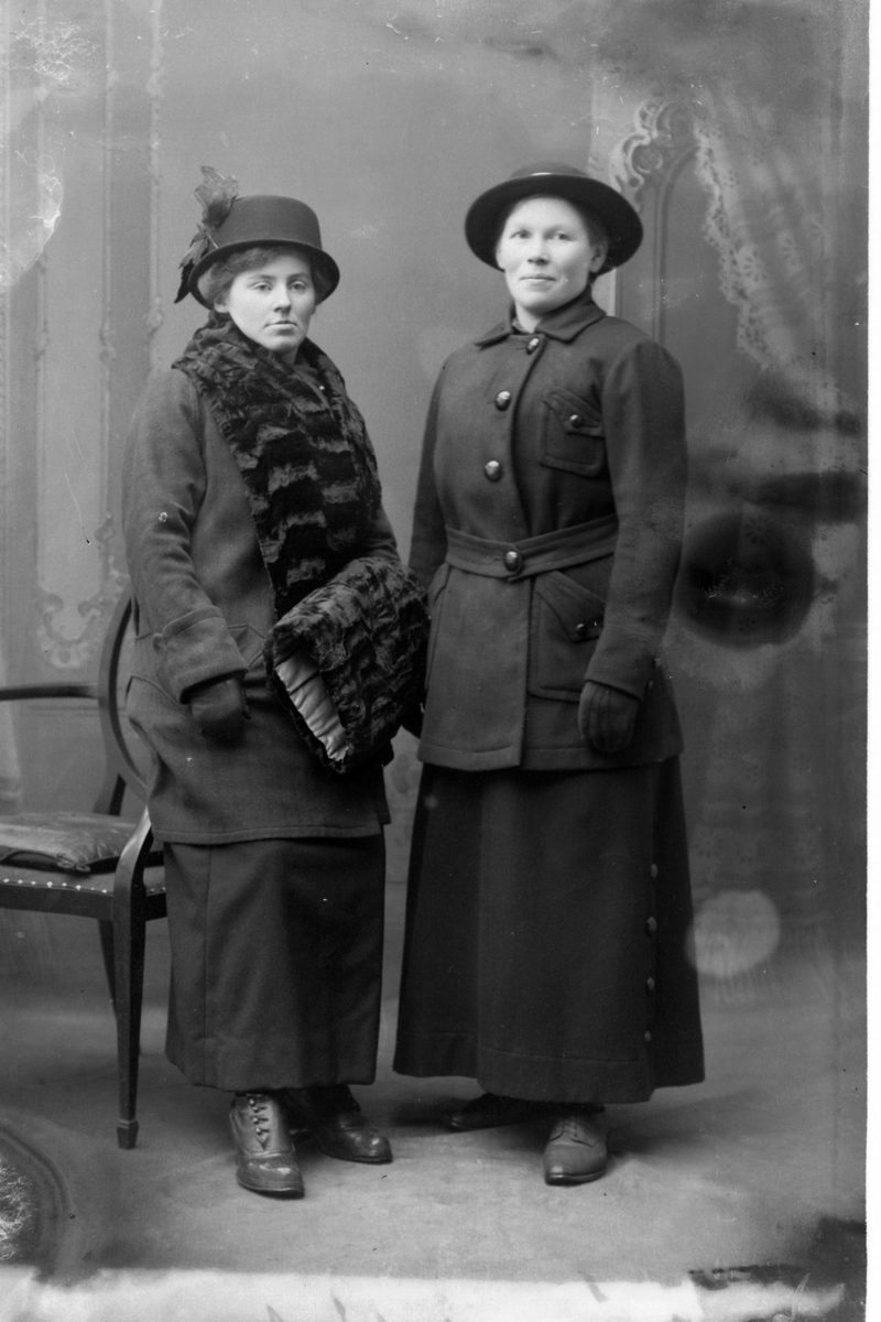 Studioportrett av to kvinner kledd i ytterklær.