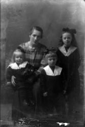 Studioportrett av en kvinne omgitt av tre barn.