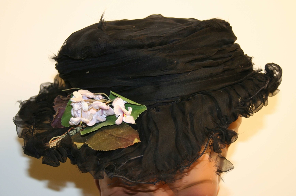 Damehatt, sydd med rynker på brem og dekor av tøyblomster.