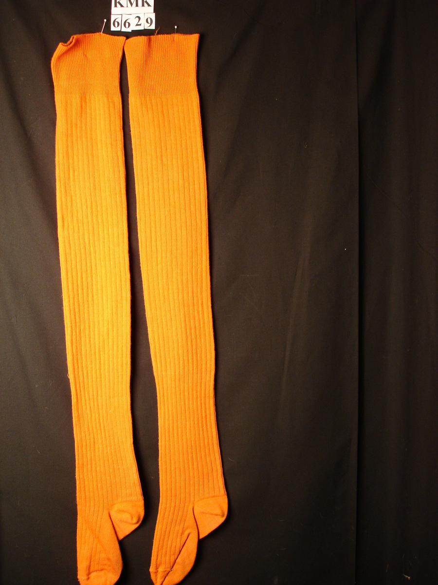 Tykke orange strikkete damestrømper, ble brukt som nattstrømper av dame født i 1911. 