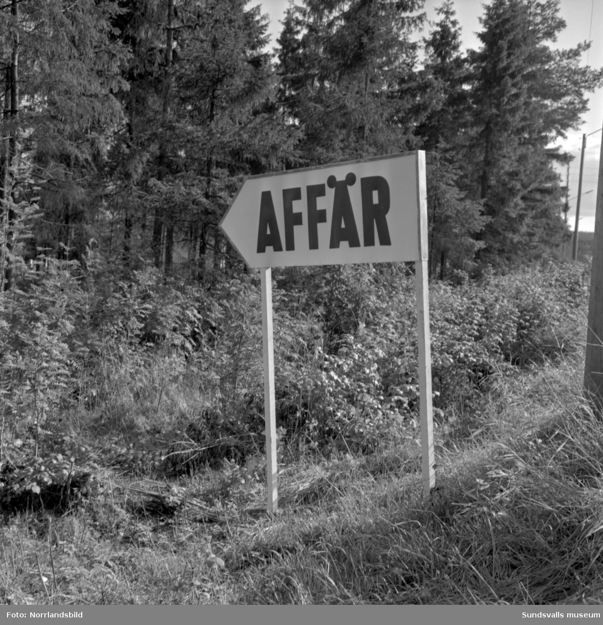 Skyltning utefter vägen mellan Sundsvall och hälsingegränsen 1961. Bland annat Bergafjärden, Dingersjö, Bredsand och Kusten. I Njurundabommen fick länge trafikanterna söderifrån lätta på gasen och anamma ett makligare tempo. Men innan vägen som nu blivit ”gamla E4:an” byggdes, var det så här som korsningen i Bommen såg ut. Längst till höger i bild skymtar det före detta bankhuset som fortfarande finns kvar.