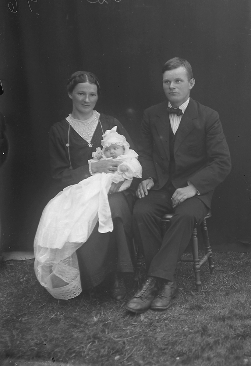 Dåpsbilde. Damen sitter og holder dåpsbarnet på fanget, mannen sitter.Sørfold. 1919.
