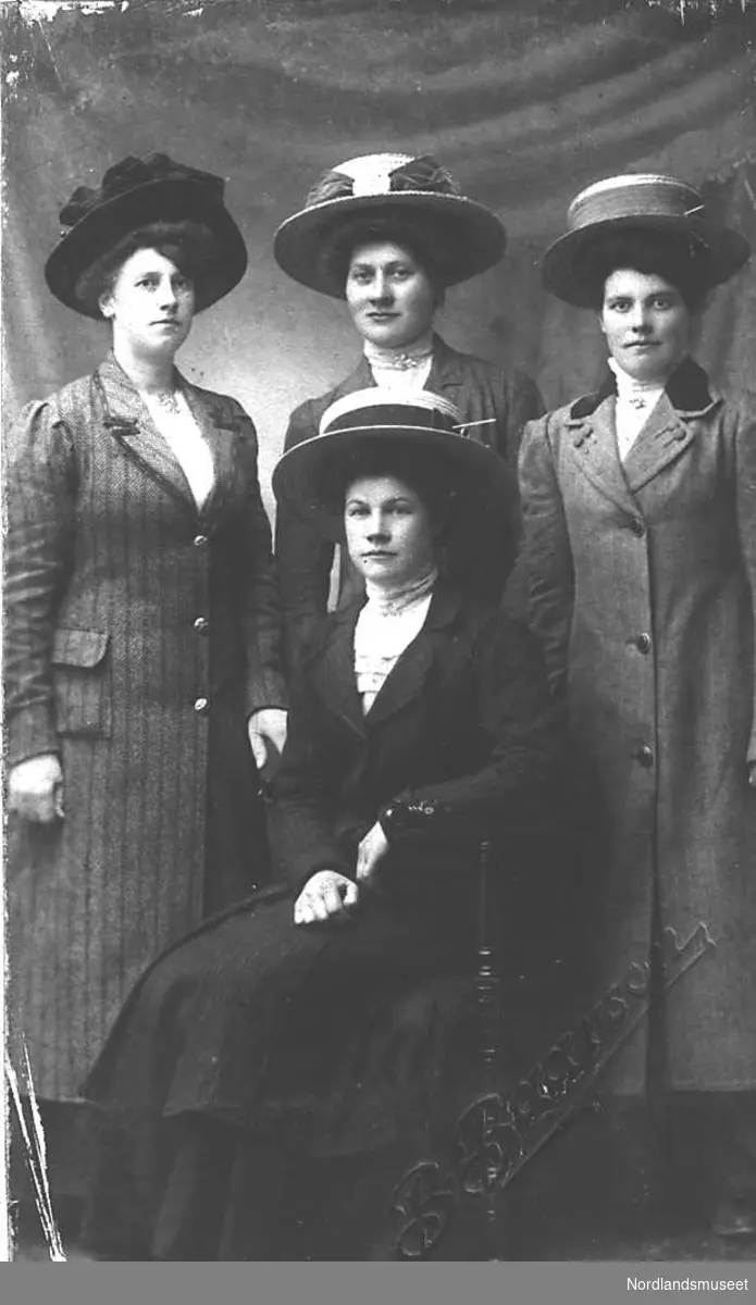 Portrett. 4 velkledde kvinner med lange kåper, flotte hatter. Bak på bildet står det " 17. Mai 1911". Bildet finnes i et album etter Pareli Endresen, f. 1881, Valle, Gildeskål.