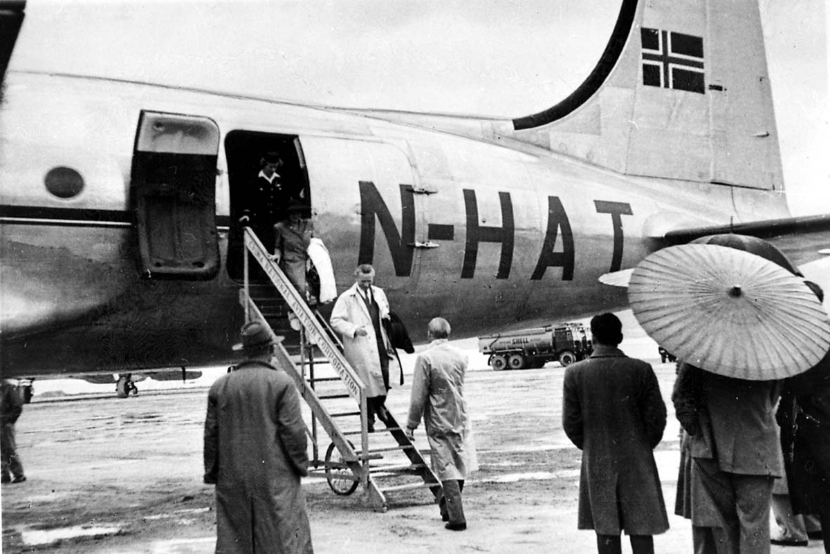 Lufthavn. 1 fly på bakken, Douglas DC-4 C-54A, LN-HAT "Norse Skyfarer" fra Braathens SAFE. Flere personer ved flyet, noen på vei ned landgangen.
