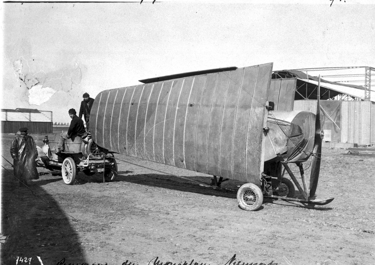 Kjøretøy og tilhenger. Transport av flyvinge til Nieuport. Tre personer ved kjøretøyet.