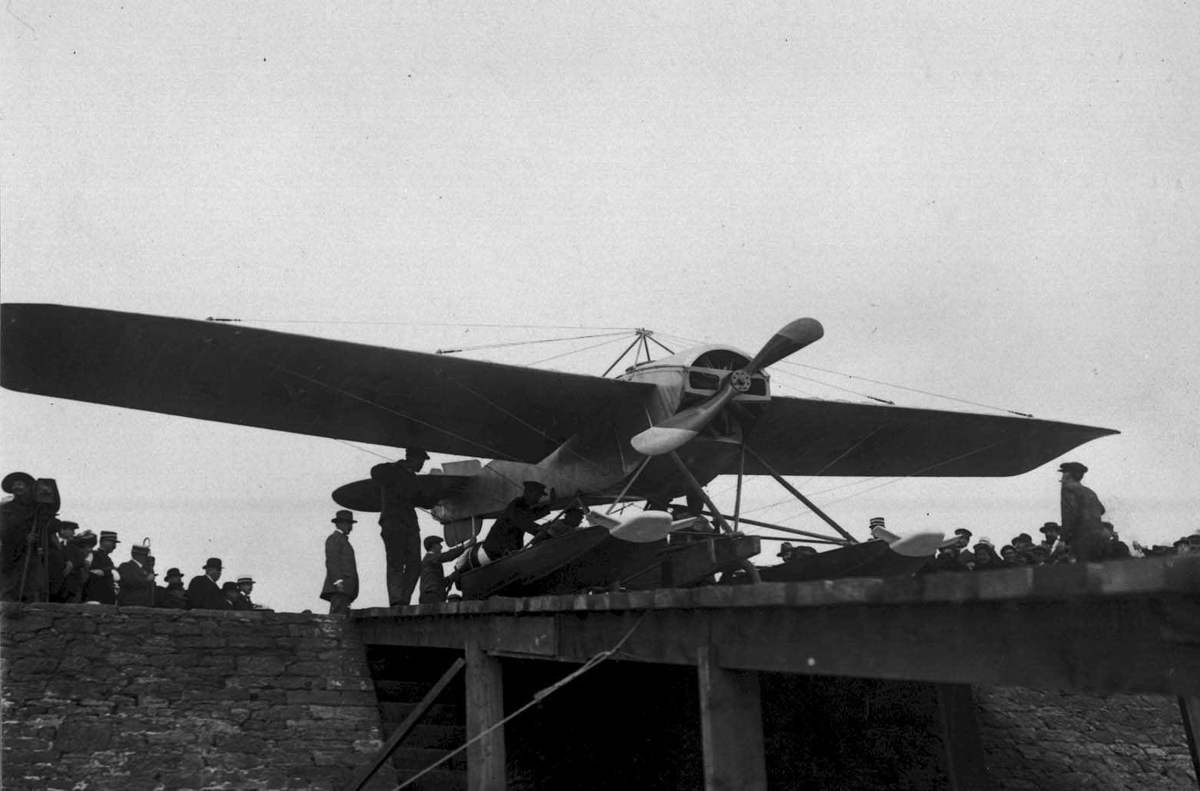 Ett fly på bakken/kai. Nieuport. Flere personer ved flyet