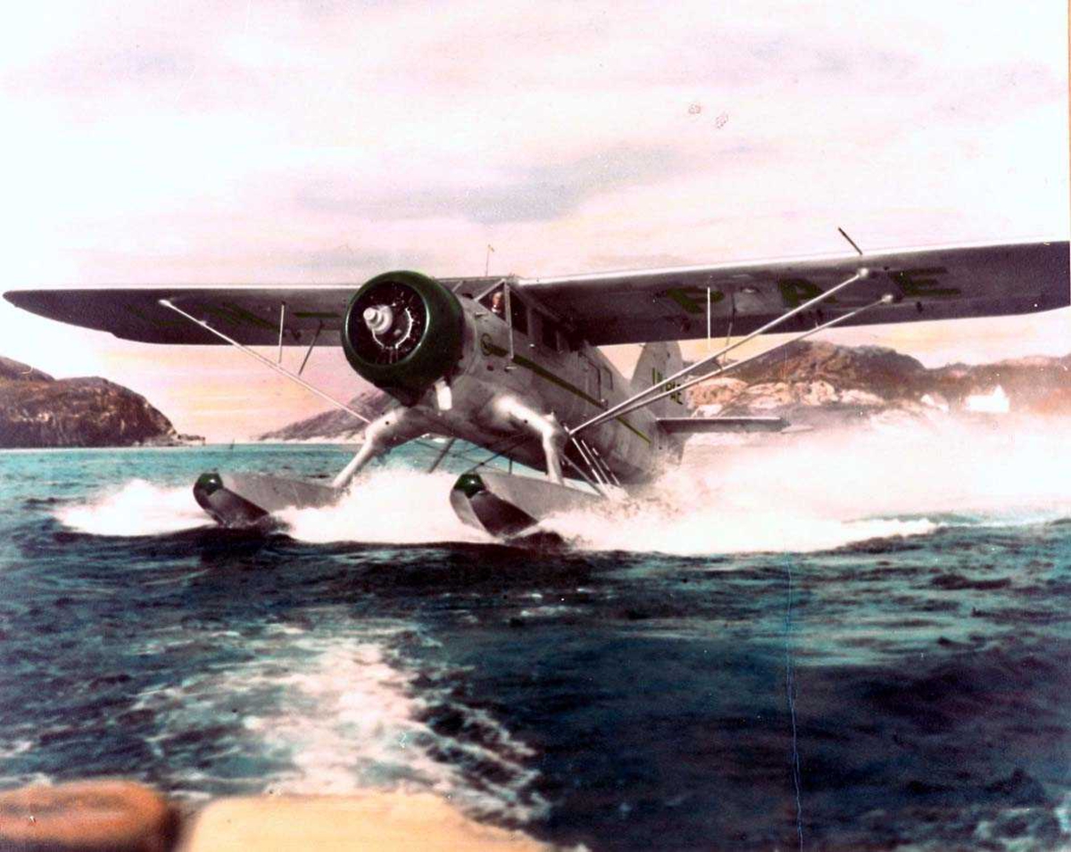 Ett fly i fart på havet, Norsemann LN-PAE, Noorduyn UC-64A-ND. Landskap i bakgrunnen 
