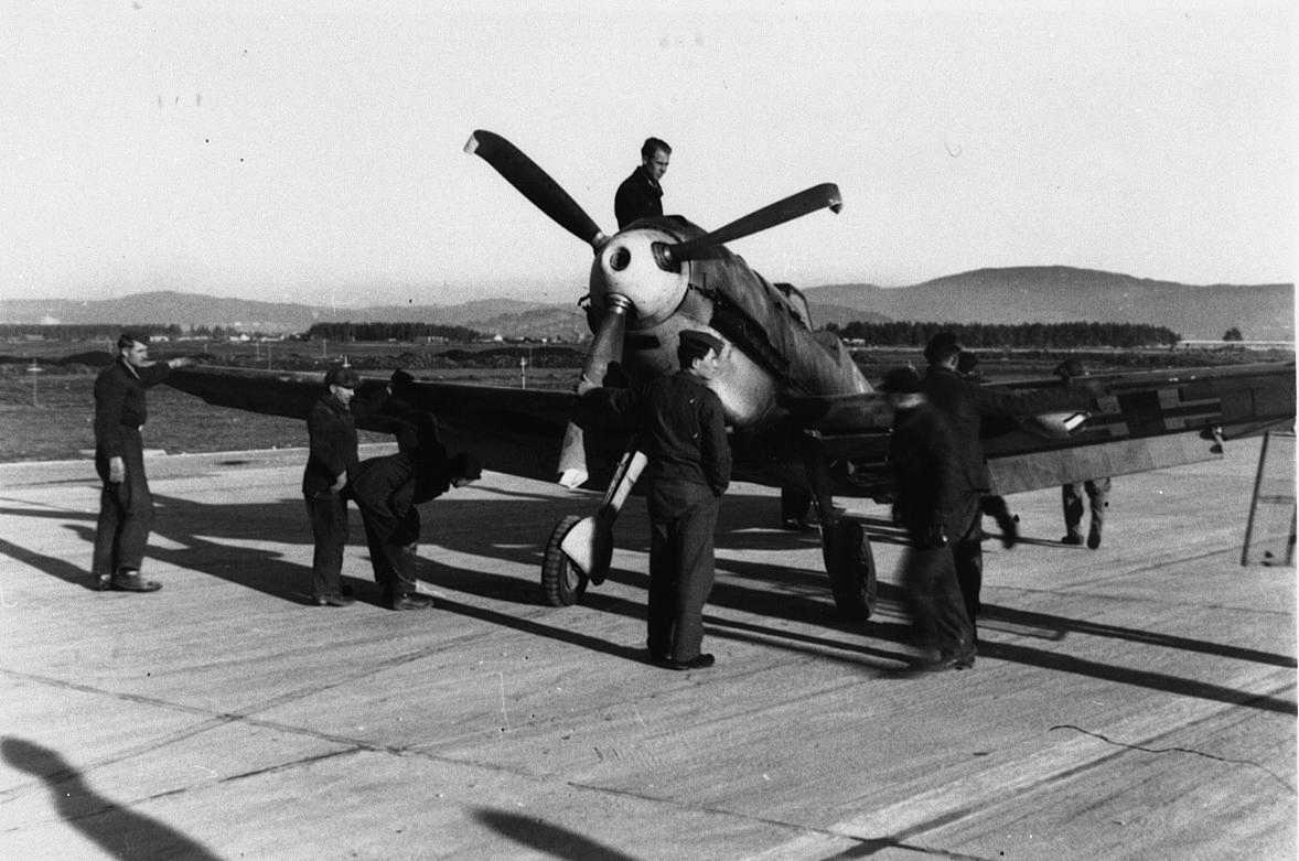 Lufthavn, tysk militert personell ved et fly. Bf109 med skadet propell.