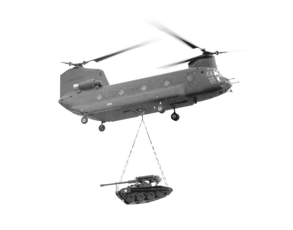 1 helikopter i luften. Boeing Chinook CH-47B. Har en tanks hendende under seg.