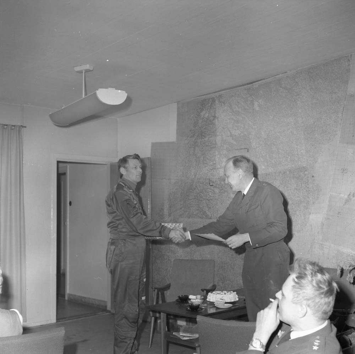 Løytnant Finn Bøe, Operasjonsgruppen, Bodø flystasjon, sees i midten og mottar gave av Oberstløytnant Alf Granviken. Sittende til høyre sees Kaptein Jan Erik Lie.
