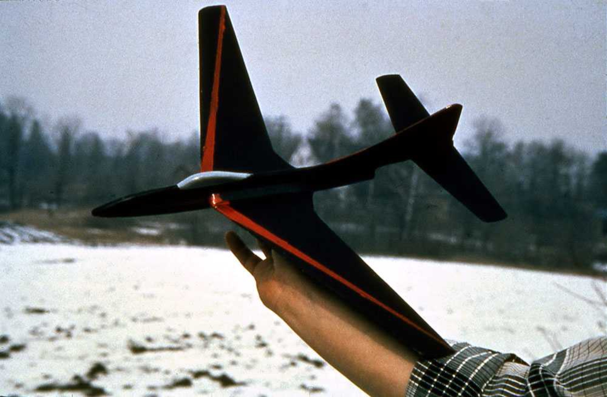 Ett modellfly holdt oppe av person. Modellens overside.
