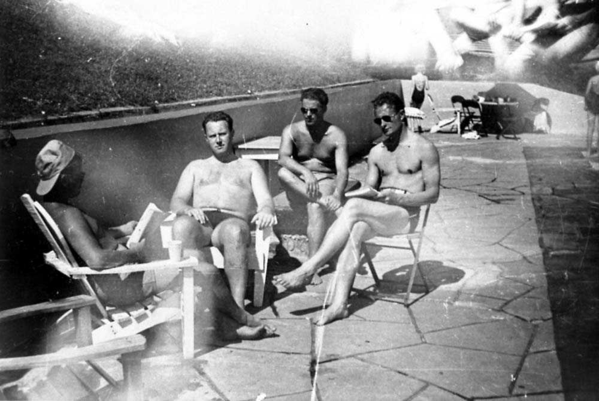Portrett. Fire personer som sitter ved et svømmebasseng, menn.
