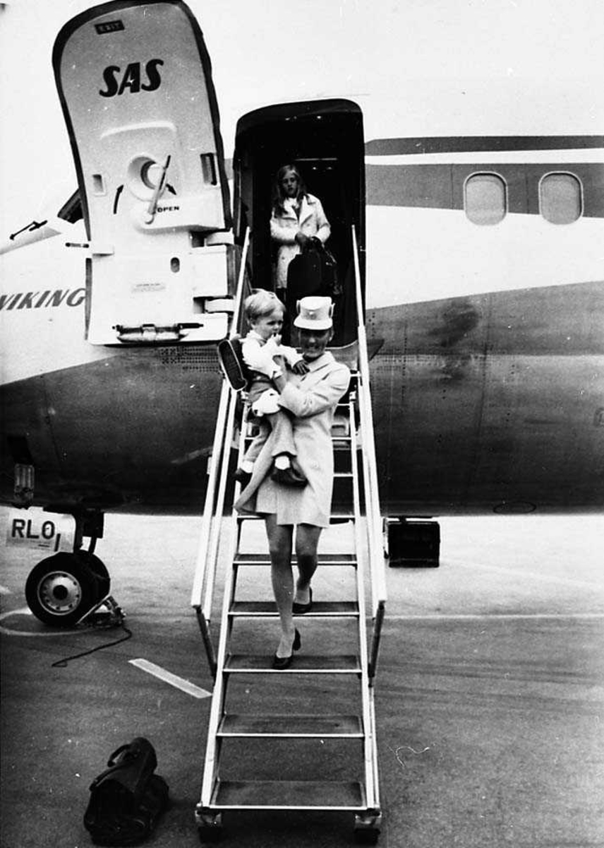 Lufthavn. En flyvertinne på vei nedover en flytrapp med et barn i armene. Et person i døråpningen til flyet, McDonnell Douglas DC-9-21 LN-RLO "Gunder Viking" fra SAS.