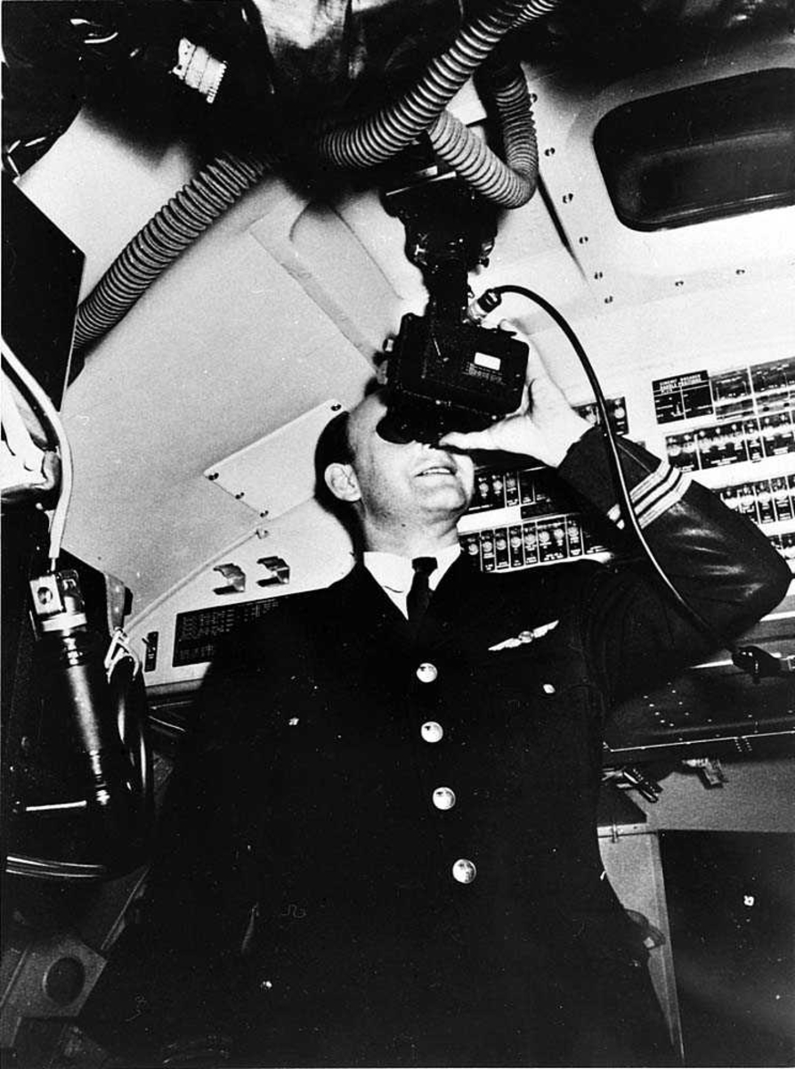 Portrett. En person i flyuniform inne i en cockpit, som navigerer.
Avleser en sekstant.