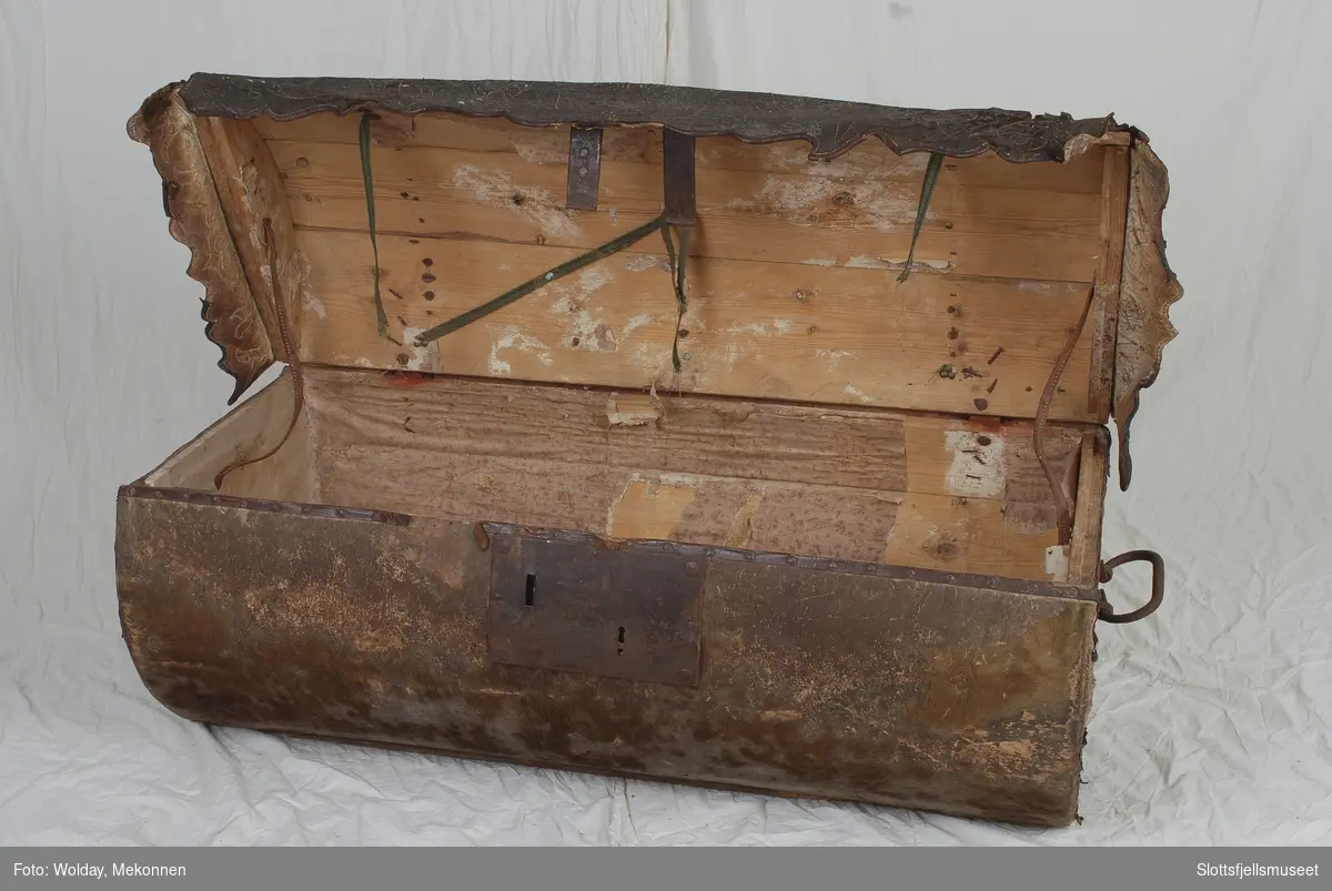 Tønneformet kiste trukket med selskinn/lær. Nederst på lokkets kanter en skinn/lær-kappe med buet kant og dekorsøm.  Innvendig trukket med mønstret papir.