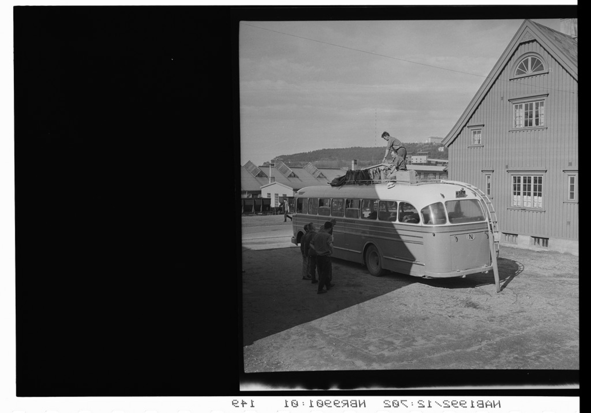 Buss. Havnegata, Narvik. Personer på og rundt bussen. Framnes i bakgrunnen.