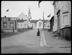 Bildet er tatt en dag med fin flaggvind, ei jente i finklær 