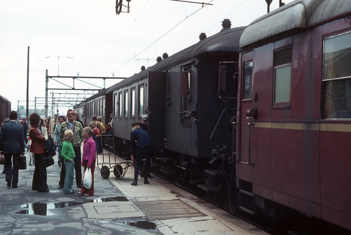 Ski stasjon. Lokaltog med motorvognsett type 65 fra Oslo Ø har ankommet. Reise- og ekspressgods blir losset ut av reisegodsvognen, BFS 65.