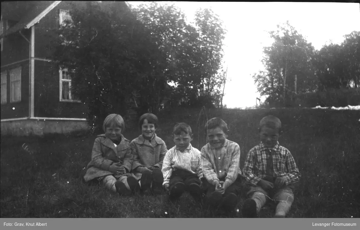 Gruppebilde, fem barn sitter på bakken.