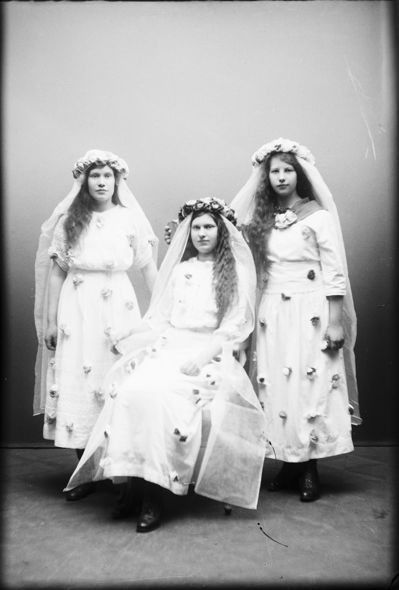 Signe (  )  Vassända-Naglum
Ateljébild där tre flickor är klädda till brudar. Alla klädda i vita klänningar med påsydda, konstgjorda blommor. De är klädd i slöja och krans.