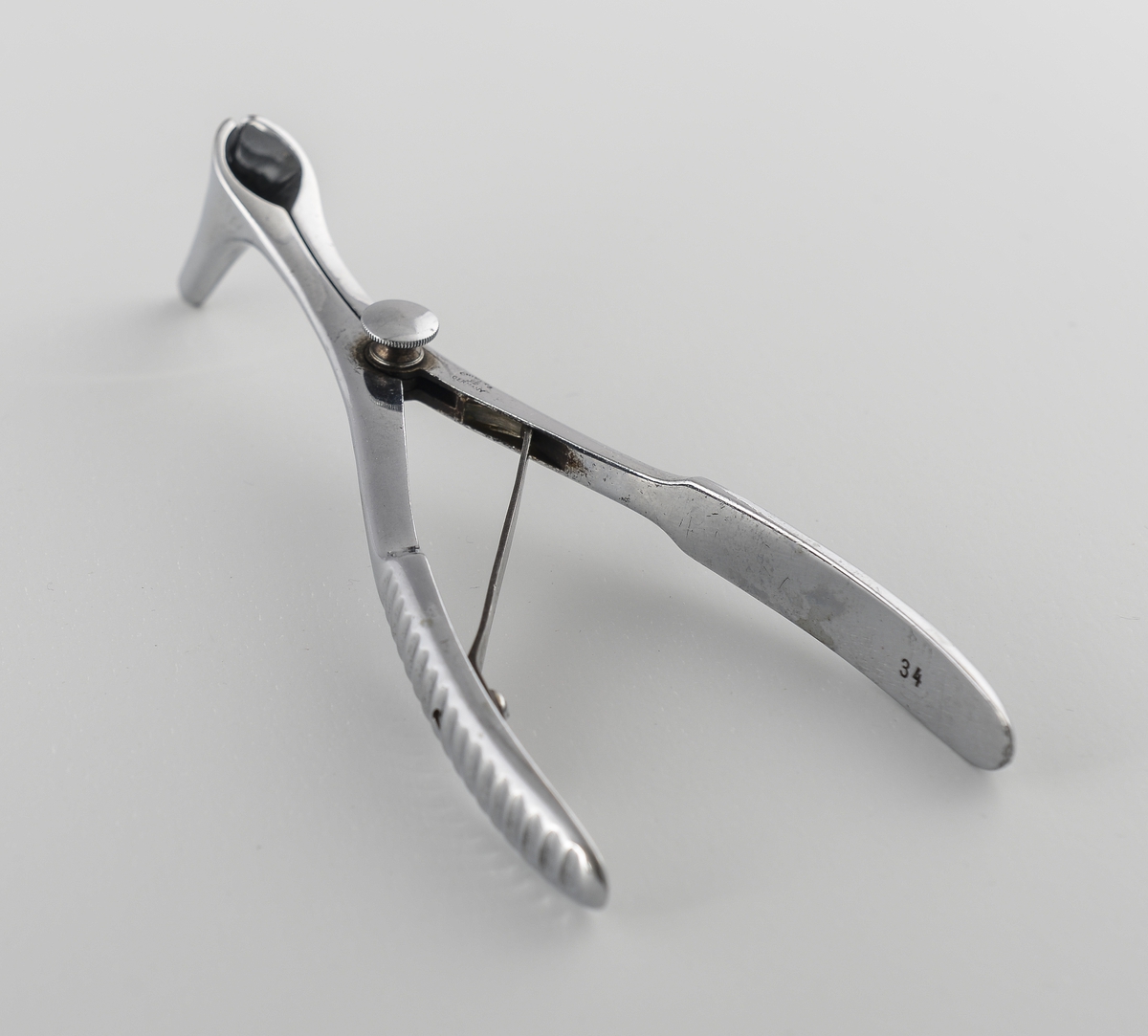 Et tanglignende metallinstrument, når man presser sammen skaftene spriker frontdelen man stikker i nesen.