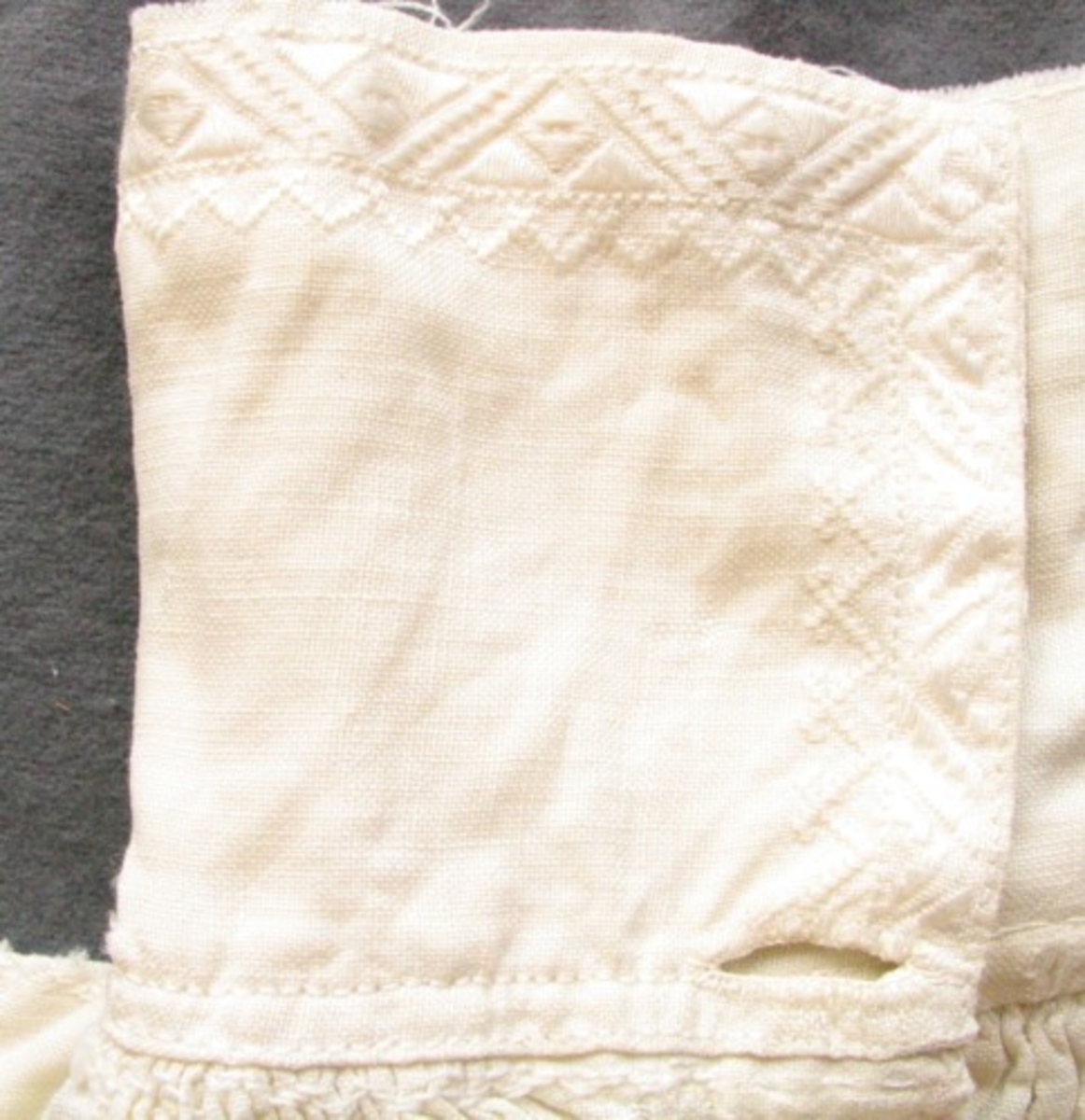 Äldre mansskjorta i handvävt linne, förmodligen brudgumsskjorta med broderat hjärta (80 X 85 mm, i korsstygn och stjälkstygn) under sprundet framtill (215 mm djupt, kantat med rosa broderier) och med märkningen "OSSMID" (9 X 62 mm) i nu rosa bomullsgarn. Krage med broderi i vitt merceriserat bomullsgarn (90 mm), broderi som bård längs kragens kanter i rätlinjig plattsöm som sträcker sig ca 20 mm in på kragen. Förstärkt ok, broderi på oket från hals till axel, rynk fram och bak vid kragen, broderi för att förstärka rynktråden. Broderi vid ärmisättningen, ärmspjäll. Stripade rynkor vid manschetten (19 mm bred), broderi på manschetten både i vitt merceriserat bomullsgarn och rött bomullsgarn, två knapphål, förstärkta ärmsprund (tyget invikt i en trekantsform). Sprund nertill i sidsömmarna (86 mm).