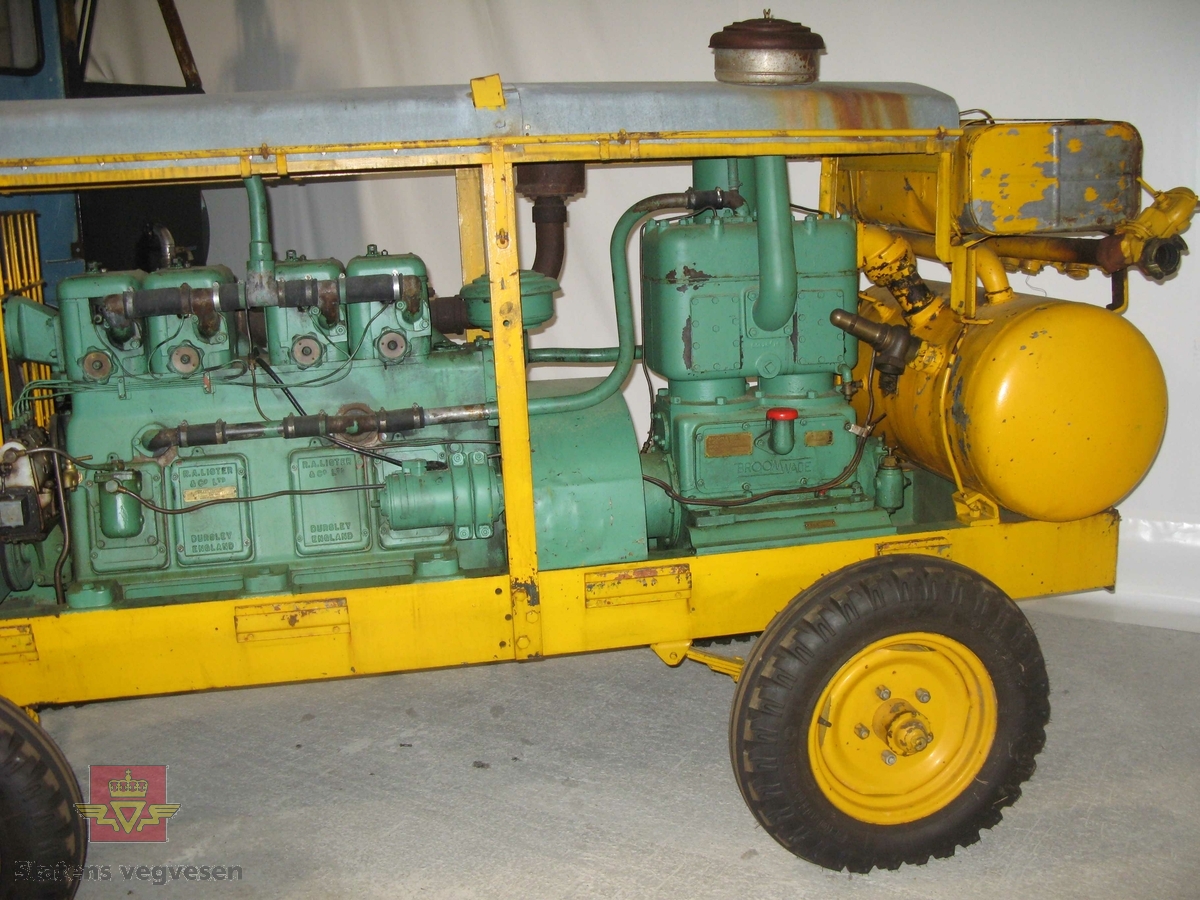 Transportabel kompressor, 2-akslet, har 4 hjul, I hovedsak grønn og gul. Bygd inn med vegger og tak. Drag i fronten, trykktank, (datert 8.6.56), og dieseltank i bakkant. Maskina har en 4-sylindret dieselmotor fra R. A. Lister, type 4-40,  som yter 40 Hk. Denne motoren driver Broom & Wade kompressoren. Merking fra produsenter og bruker.

