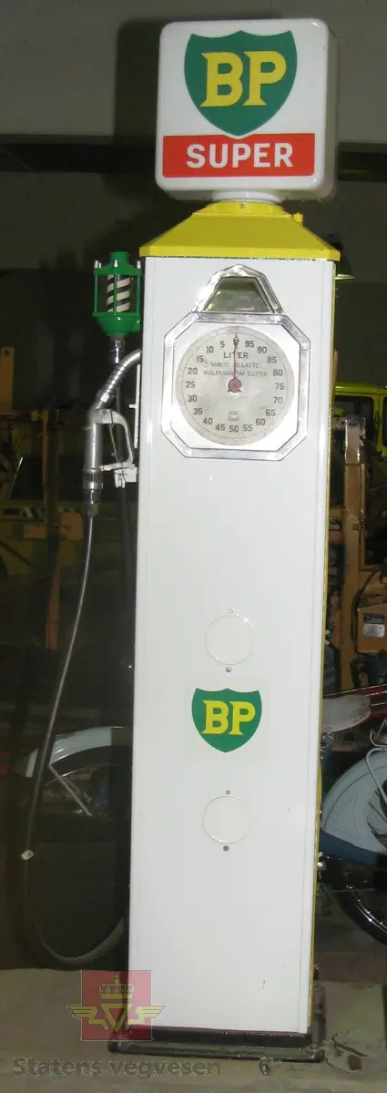 Hovedsakelig hvit og gul bensinpumpe, med logo fra BP. Elektrisk drevet med lyspære i toppen. Kan fylle opptil 100 liter om gangen.  Pumpa har diverse merking. I oppusset stand. Pumpa er montert på en sokkel av betong.