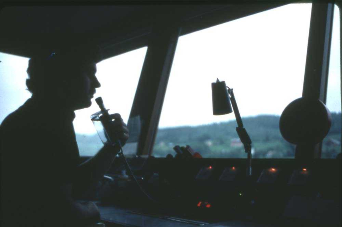 Lufthavn. Førde/Øra. Flytårn. En person, AFIS-betjenten i tårnet gir informasjon til et fly i nærheten.