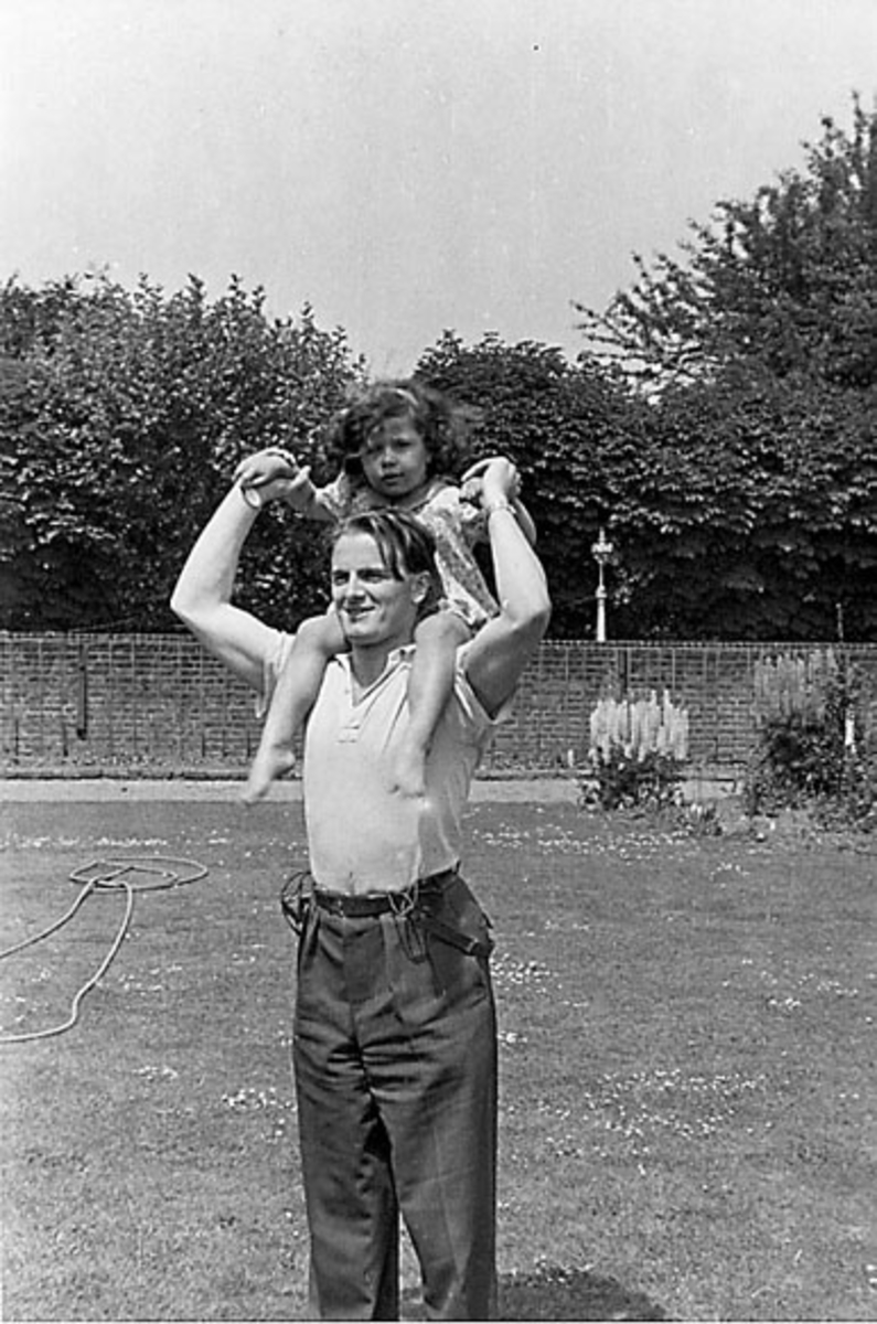 Portrett, en person, ant. i en park, med et barn på skuldrene.