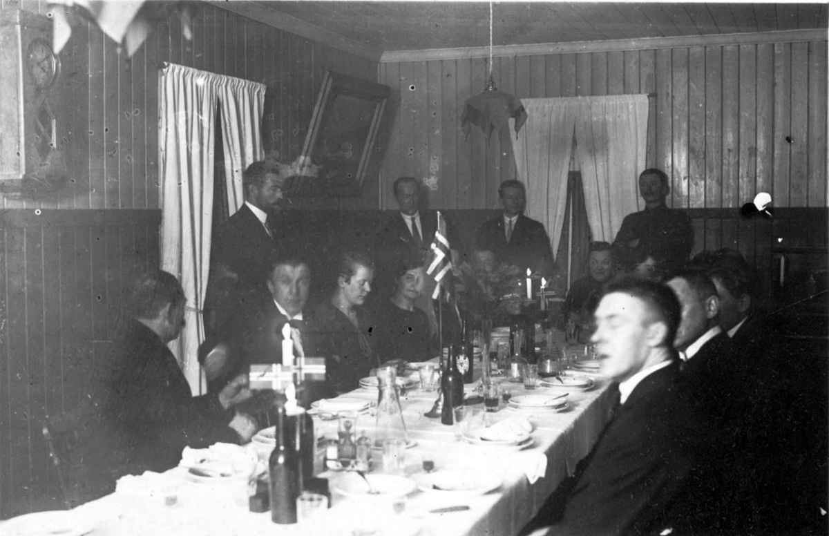 Selskap, festdekket bord med norske flagg. Kan være julefeiring 1925. Flere personer rund bordet.