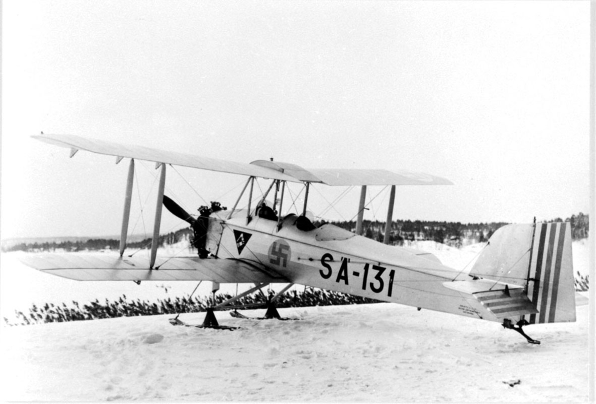 Fly, propellfly, dobbeldekker Sääski II, SA-131, med hakekors symbol på siden. Flyet med skiunderstell, står på bakken. Snø.