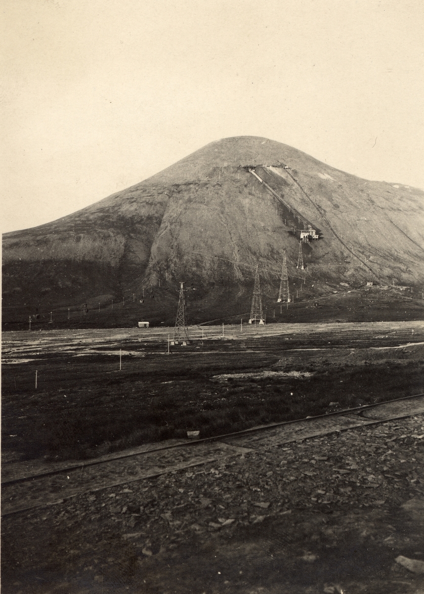 Gruveanlegg i fjell på Svalbard. Jernbanespor i forgrunnen.