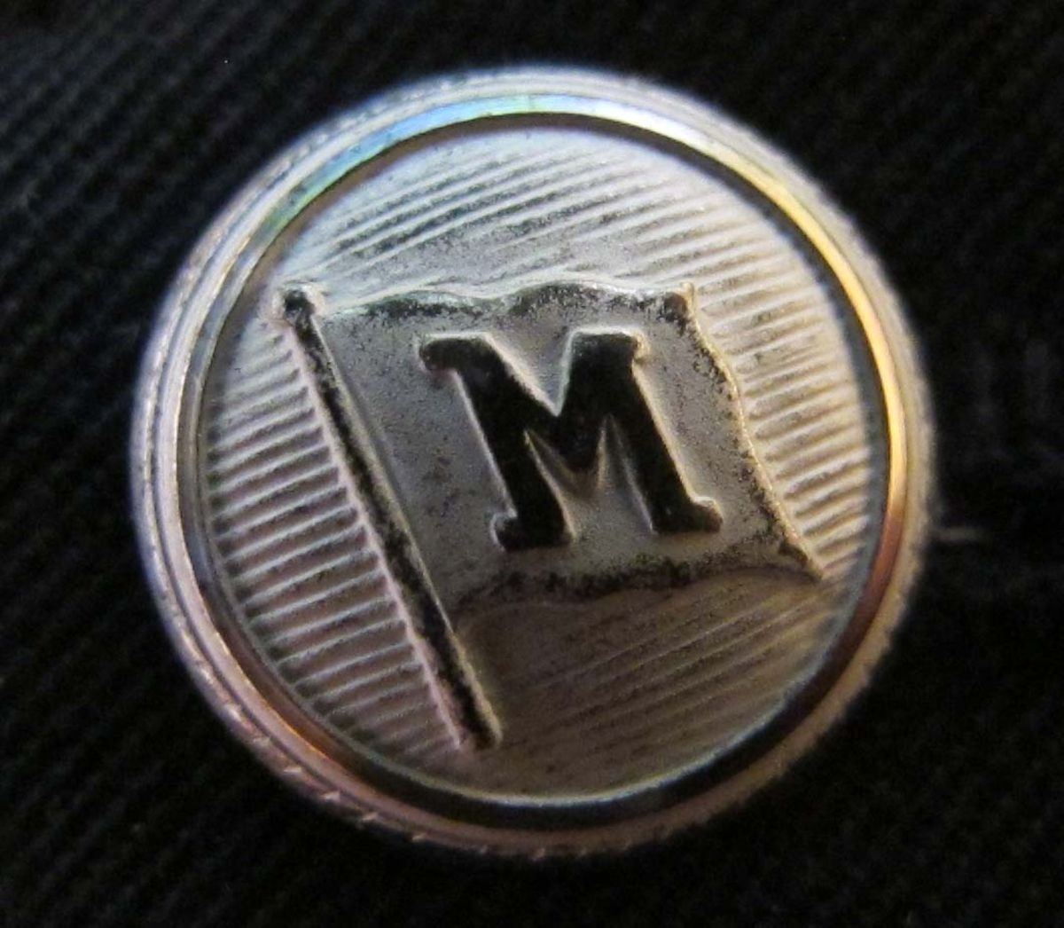 Axelklaffar med rederiknapp Myrsten (silverfärgad knapp med M i flagga) samt tre galoner för funktionschefer: hotell-, restaurang-, köks- och butikschef.