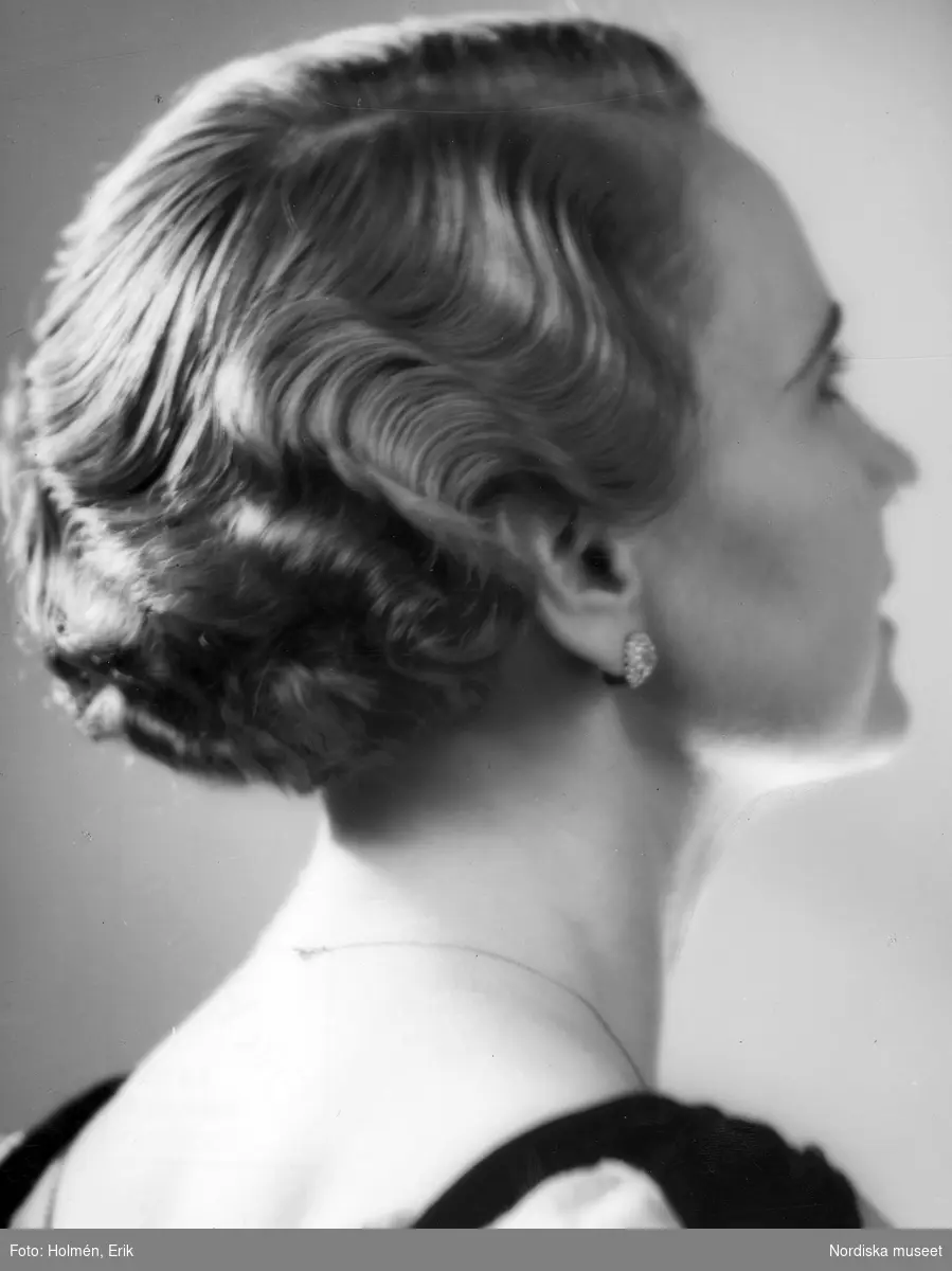Fru M. Oldenburg i lagd frisyr, örhänge och halsband.