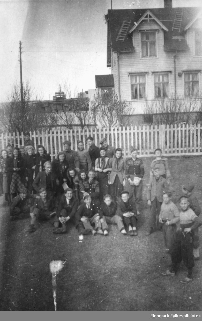 Middelskoleelever i Vadsø 1946-1947. Bildet kan være tatt ved Prestelva. Det ser ut til å være en bro på veien som går på oversiden av huset