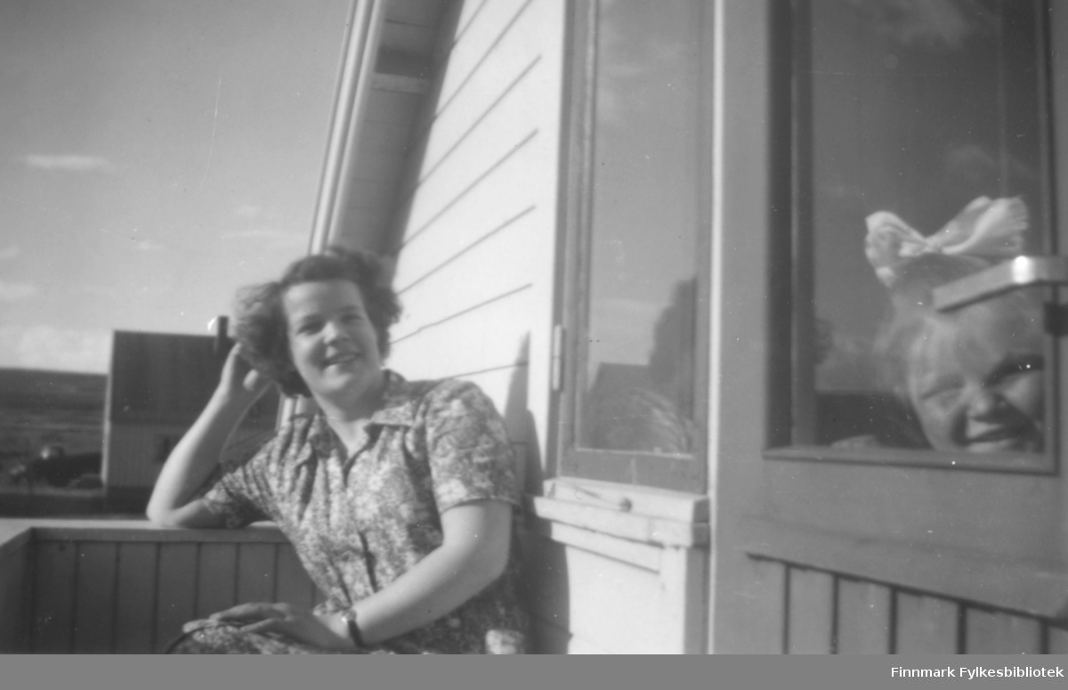 Ragnhild Ebeltoft fotografert på verandaen til familiens hus i Fosseveien. I vinduet ser vi ei lita jente, Dagmar