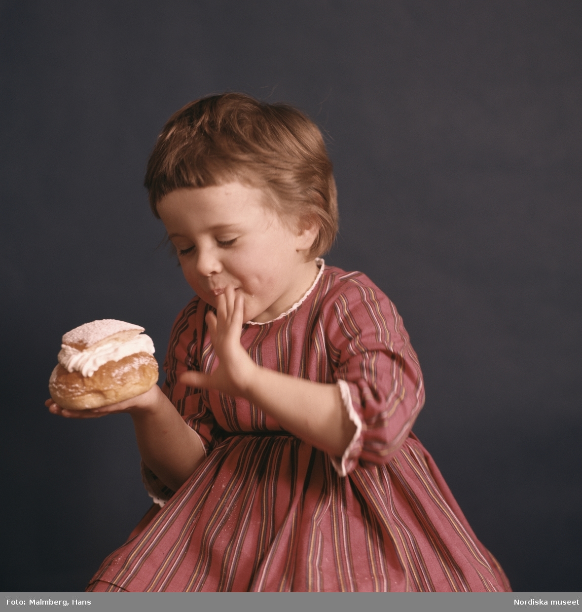Studioporträtt: "Barn äter semla: reklam." Fettisdagsbulle.