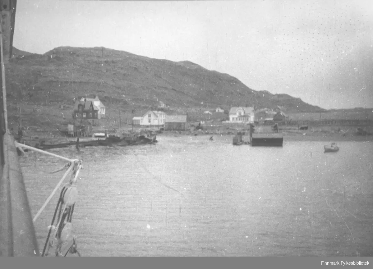 Kongsfjord sett fra sjøsiden. En båt ligger på sjøen et stykke fra land.