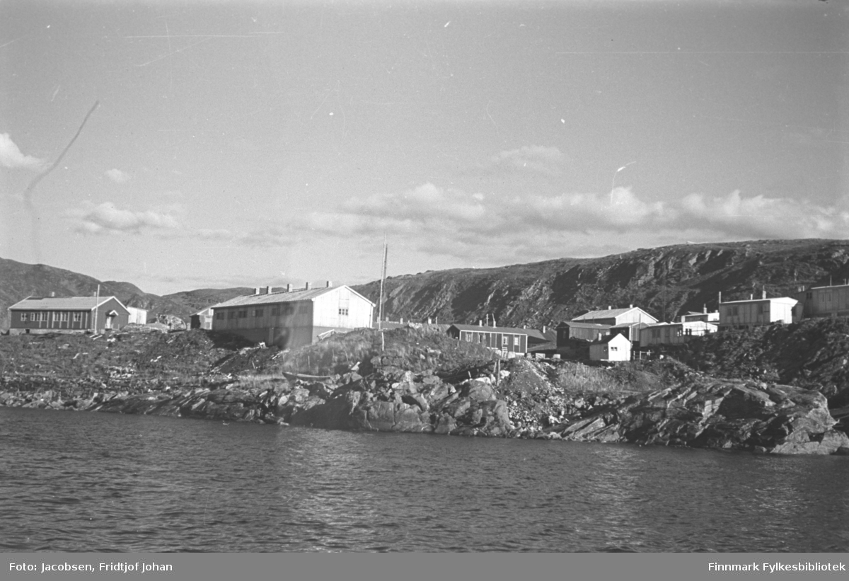 Området Batteriet i Hammerfest fotografert fra sjøen. Flere brakker står på området og opp mot bydelen Haugen. Helt til venstre ligger Postverkets funksjonærbolig. Fjellet i bakgrunnen er Salen.