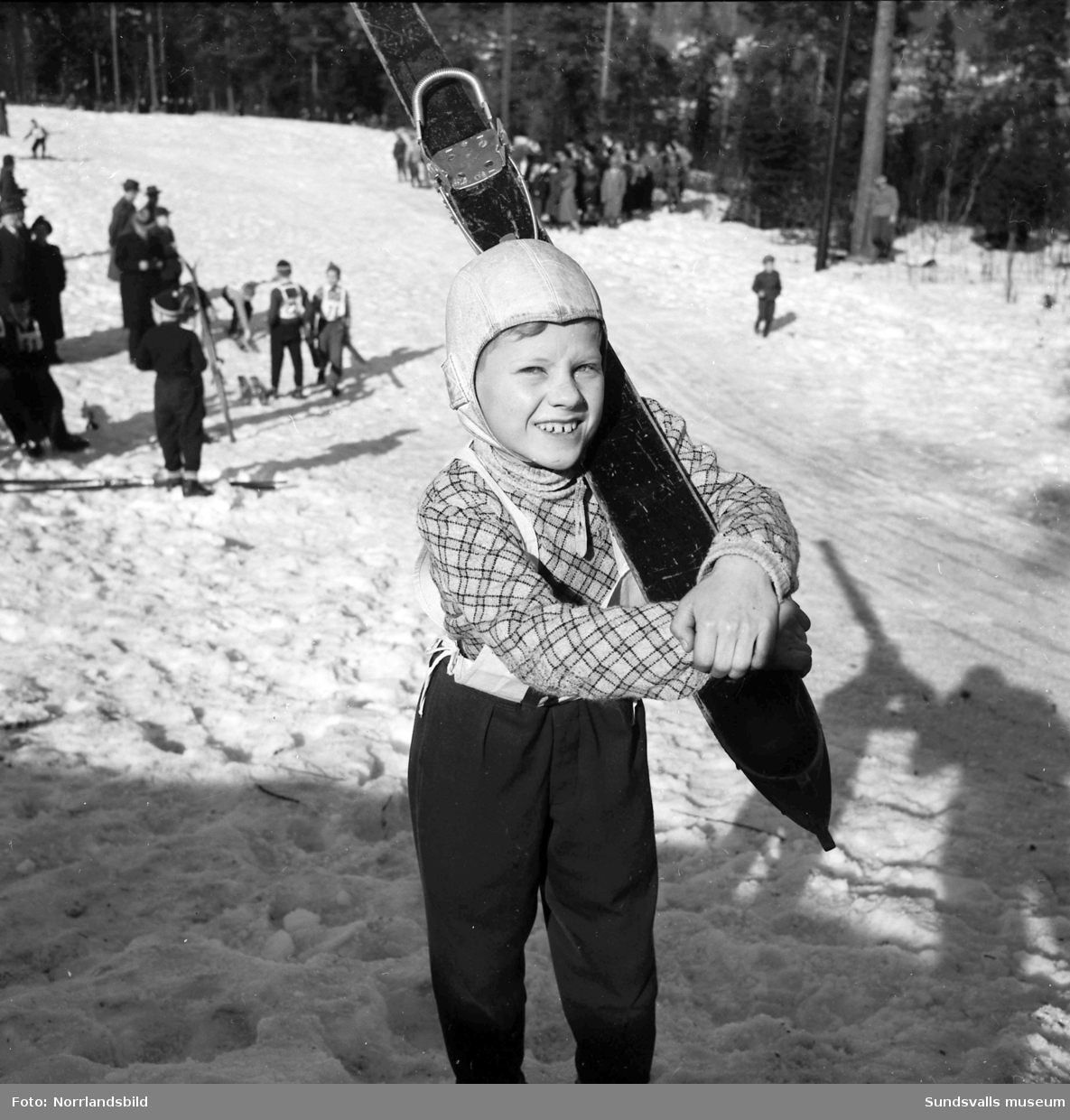 En stor bildserie från Ungdomens vinterspel i Sundsvall 1953. Längdskidor, backhoppning (i Vidarbackarna vid LV5), utförsåkning samt prisutdelning. På bild 7 ses backhopparen Sven Selånger instruera pojkar i hoppteknik.