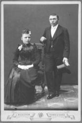 Portrett av et par. De er pent kledt. Bildet er tatt i et at