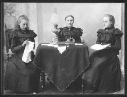 Gruppeportrett av tre kvinner. I midten sitter Anna Christin