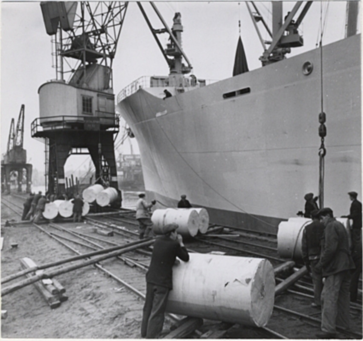 Lastning av papper i Norrköping november 1947. Pappersbalar rullas fram på kajen och lyfts ombord.