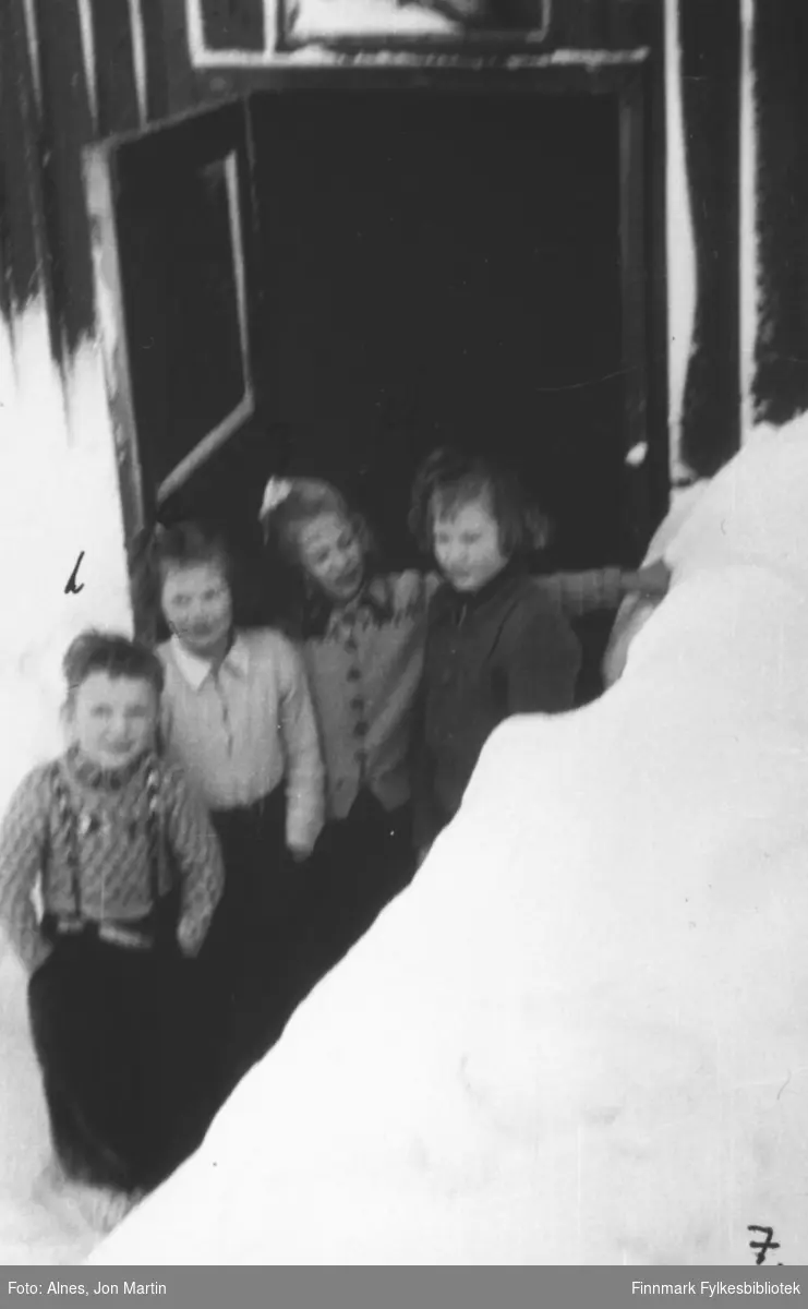 Elever ved inngangen til skoleinternatet i Øksfjord, vinteren 1954. Fra venstre: Roar Mauseth, Aina Olsen, Kirsten Nilsen, ukjent