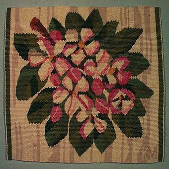Bildväv med motiv av små rosa-vita blommor mot bakgrund av blad i flera olika gröna nyanser. Varp i lingarn och inslag i ullgarn. Monterad med langettkant.